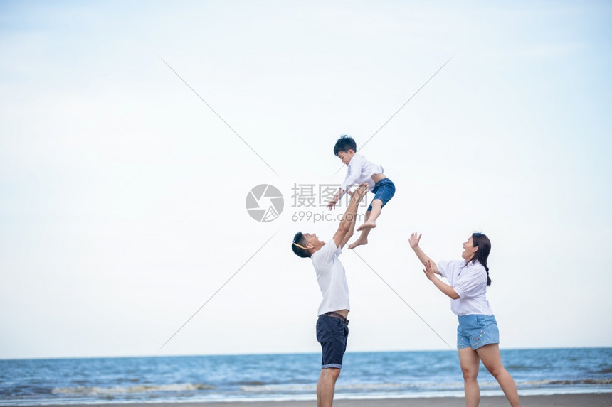 幸福的一家三口在海滩上玩耍图片