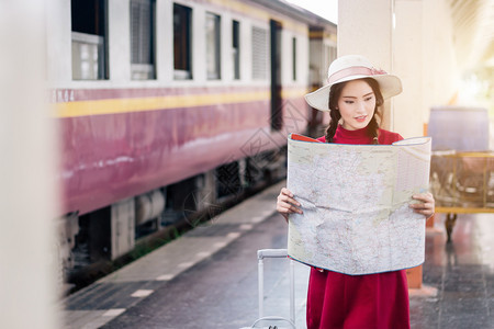 身着红色礼服并携带行李的亚洲妇女怀孕看火车站旅行孩子独自的爱图片