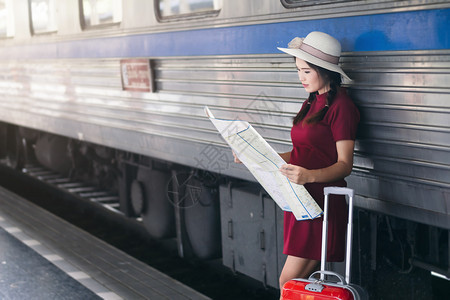 身着红色礼服并携带行李的亚洲妇女怀孕看火车站旅行游亚洲人女士图片