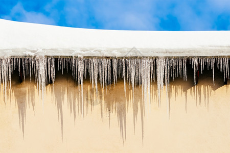 屋顶盖在雪和危险冰柱中圣诞节寒冷的天空图片
