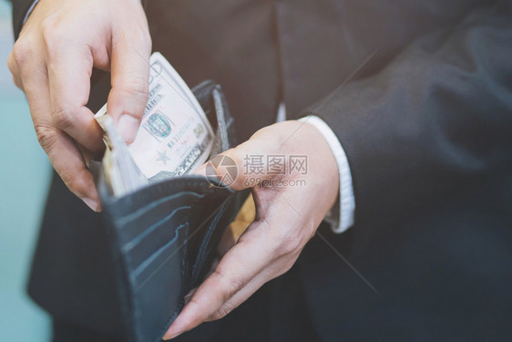 常设投资债务男人站着拿黑皮夹在城市里有钱图片