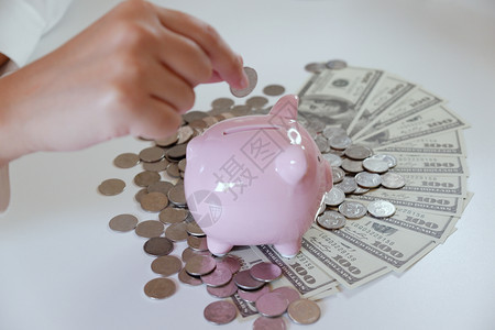桌子增加人们用硬币和钱把放进小猪银行收入图片