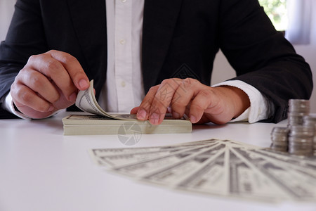经济利润商人在办公桌上用硬币和钱数钞票财富图片