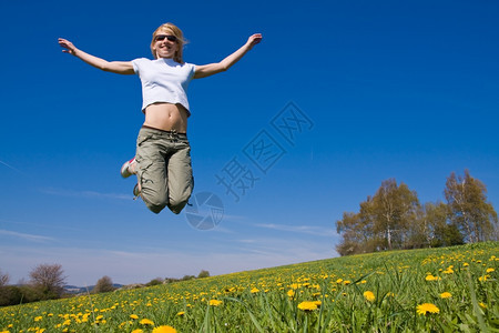 年轻女子在花朵茂盛的草原上玩得开心笑健康活力图片