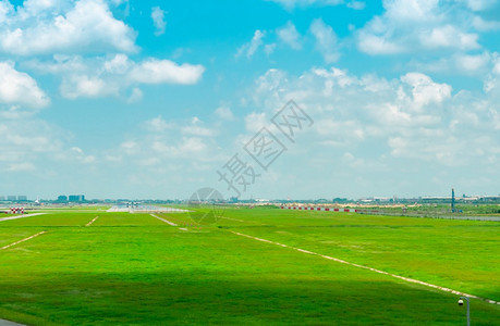 运输机场跑道和绿草地的景观蓝天空和滑行飞机上的白云空中飞机在场航空业务的滑行道上起飞机场正绕行的城市风景场地商业的图片
