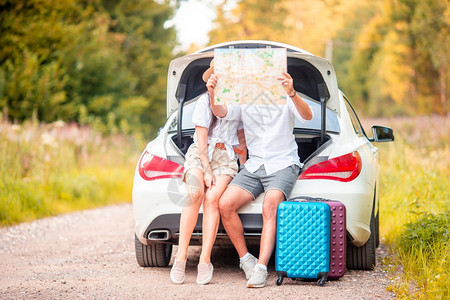 运输年轻旅行者坐在一辆汽车的后备箱中看享受暑假的旅游者青年夫妇过暑假光白色的小狗图片