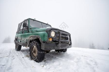 雾中雪山上的绿色旧越野车雪山上的绿色旧越野车旅行冬天安全图片