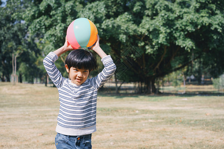 亚洲男孩在草坪上玩耍公园里球是户外的男人肖像愉快图片