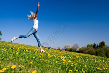 闲暇天空年轻女子在花朵茂盛的草原上玩得开心美丽图片