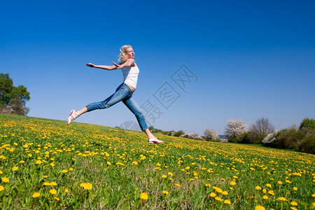 学生金发未来年轻女子在花朵茂盛的草原上玩得开心图片