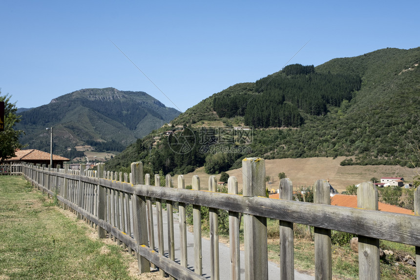 玩在一个草地的木篱笆中背景里有山峰的阿斯图里亚Asturias地面图片