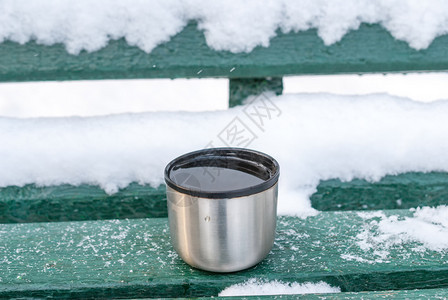 木头金属杯和热饮在雪盖的长椅上明亮食物图片