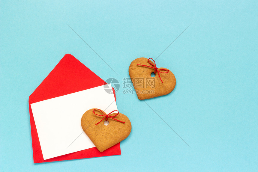 红信封空白纸卡用于文字和心形姜饼干放在蓝背景上翻版空间错装用爱的红信封打喜悦黑白纸卡放在蓝背景上象征信息烘烤的图片