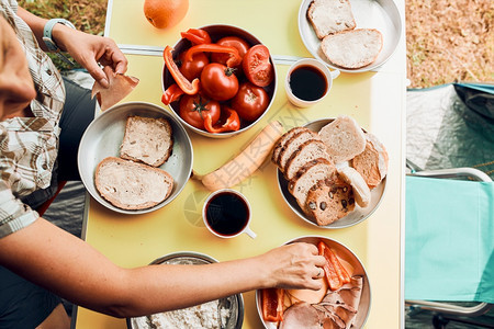 暑假期间准备的露营面包干酪冷肉番茄水果和咖啡杯的早餐图片