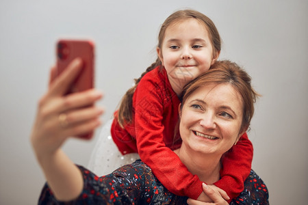 制造微笑相机母亲和女儿用手机打视频电话保持距离与家人的亲友聊天玩着自拍照使用智能手机与家人远程连线时家庭乐得开心人愉快在聊天中分图片