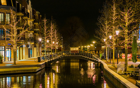 窝AlphenaandenRijn市中心的运河桥荷兰城市建筑无地装饰有灯光的树木荷兰城市建筑晚上图片