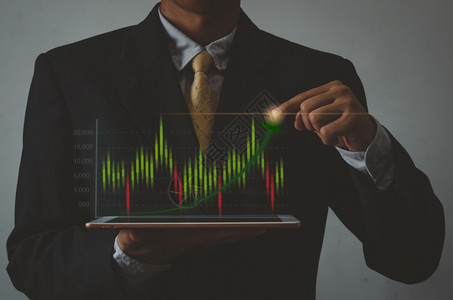 持有手平板牌和图示表股票市场的商人虚拟屏视投资业务和概念金融利润数字的男人图片
