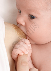 新生婴儿吸母亲的乳房紧抓住她的手指母乳喂养浅度的外劳团结美丽脸图片