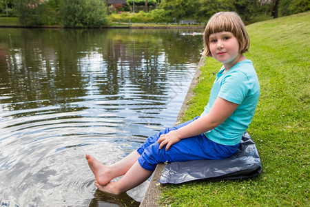 腿喜悦乐趣坐在公园池塘水中与脚同坐的年轻荷兰女孩图片