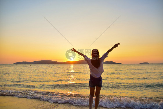 美丽的太阳黎明站在海边滩上的妇女在晚金时日落的背景下在泰国旅行暑假沙滩上站着图片