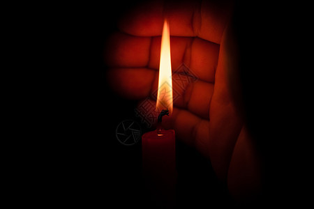 美丽的灵手保护蜡烛的灯光防止黑底暗中的风证明图片