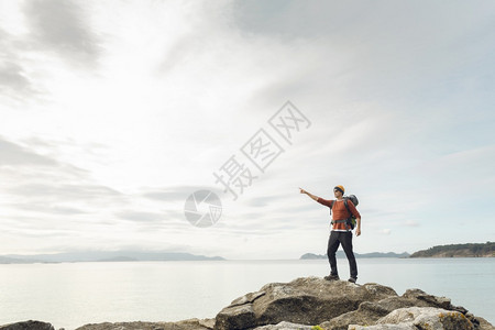 带着背包的人享受指向美丽的海岸清晨风景沉思指点早晨图片