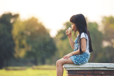 人们黑发白布坐在面带冰淇淋边吃着甜美公园背景的黑发白布夏天格林图片