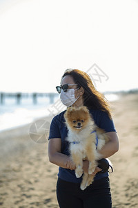 享受年轻女子和她的狗在海滩上晒日光浴白种人所有者图片