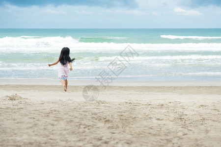 女孩在海滩和浪上玩沙子时穿着白裙的小女孩黑发头享受模型孩子们图片