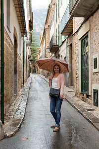 在狭窄的欧洲街道上拿着雨伞的女孩快乐微笑天气图片