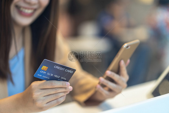 数字的主持人扫描利用信卡与移动手机在百货商店网上购物的亚洲妇女通过服装店背景技术钱财包和在线支付概念信用卡模型对服装店购买线上物图片