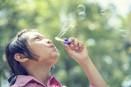 快乐可爱的女孩在夏季户外绿色游乐场玩耍泡沫在公园快乐时光中欢笑愉快的女孩在自然公园吹肥皂的泡闲暇乐趣快的图片