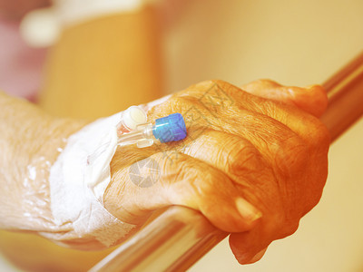 卫生保健在医院病人中用针塞在盐碱药剂中使用的有盐碱静脉注射IV溶液的老年人手与盐碱静脉注射药物导管图片