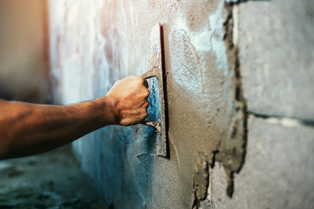 工具行业石匠人们在建筑房屋墙上涂水泥的紧手图片