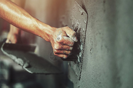 石膏硬件使固定工人们在建筑房屋墙上涂水泥的紧手图片