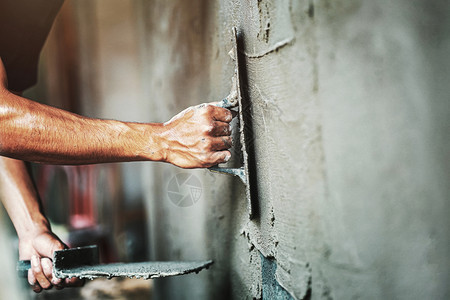 修理重量工人们在建筑房屋墙上涂水泥的紧手改进图片