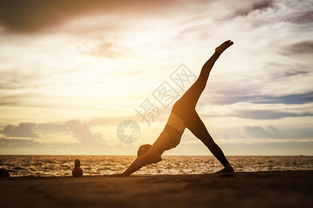 身体女孩轮廓在超现实日落的海边健康概念和锻炼中在超现实日落期间从事瑜伽的妇女图片