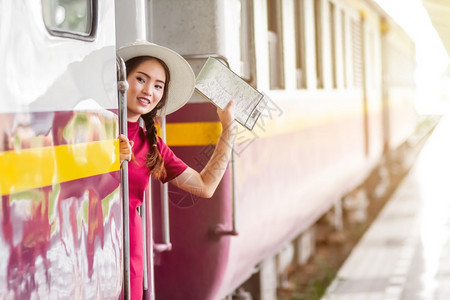 产假窗户身着红裙子的亚洲孕妇持有和手举在火车站旅行中打个招呼亚洲人图片