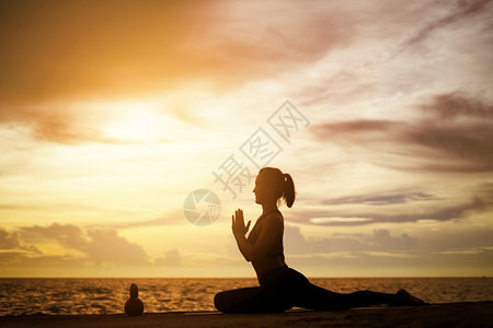 松弛在超现实日落的海边健康概念和锻炼中在超现实日落期间从事瑜伽的妇女户外人们图片