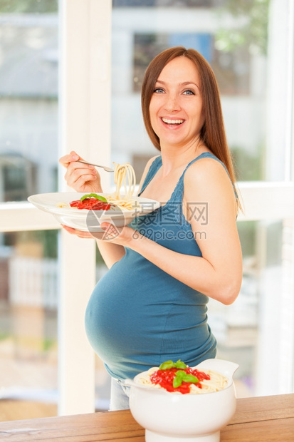 饥饿的盘子产前孕妇用番茄酱吃大部份意利面粉的相片图片