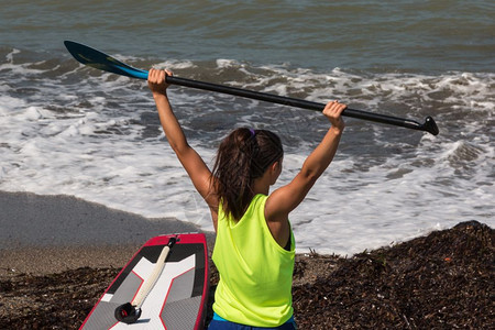 风女孩在冲浪前伸展她的手臂肌肉和奥尔站起来划桨闲暇冲浪板图片