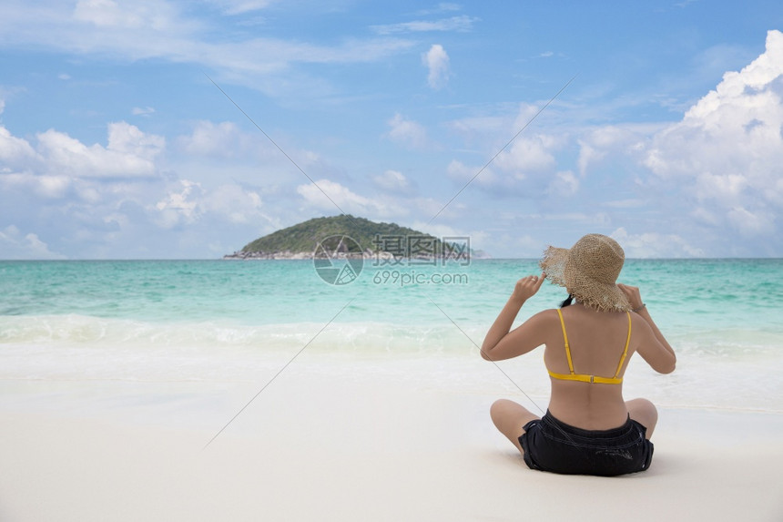 自然身后放松的比基尼女在沙滩上戴着阳光草帽在热带暑假旅行中看着海洋亚洲坐图片