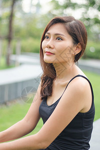 泰国年轻的幸福那女人坐在公园里欢笑着微图片