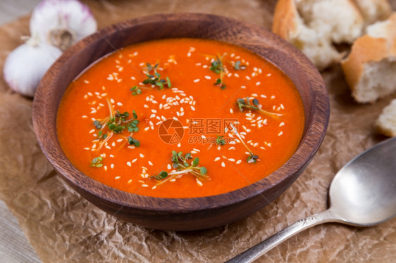 西红柿橙粉碎棕纸上木碗中的番茄汤素食主义者图片