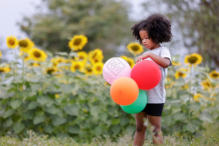 一个小卷发女孩在户外玩气球爱金发女郎漂浮图片