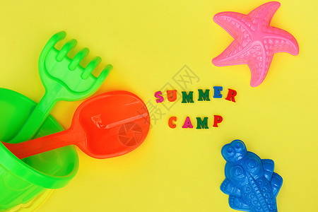 塑料玩具文本夏令营和五彩套装儿童玩具适合夏季游戏在沙箱或黄色背景的沙滩上创意顶视图平躺概念儿童休息和发展文本夏令营和五彩套装儿童玩具适合背景