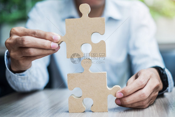 木头不完整男人手在桌子上连接情侣拼图商人在办公室里拿着木拼图商业解决方案使命目标成功和战略概念匹配图片