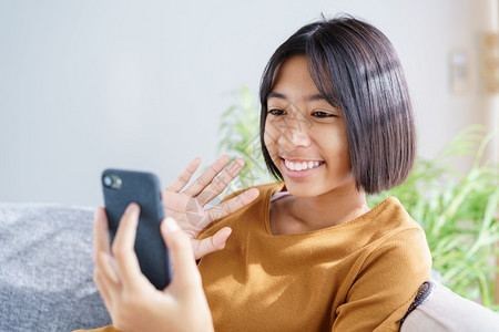 亚洲快乐的小女孩视频呼来智能手机坐在家中客厅时挥手打问候招呼家庭放松和生活方式概念AC54970孩子们细胞亚洲人图片