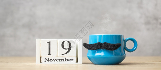 马克杯黑色的或者国际男子日1月9历蓝咖啡杯或茶和黑胡子装饰品在桌边快乐父亲节和庆祝概念图片