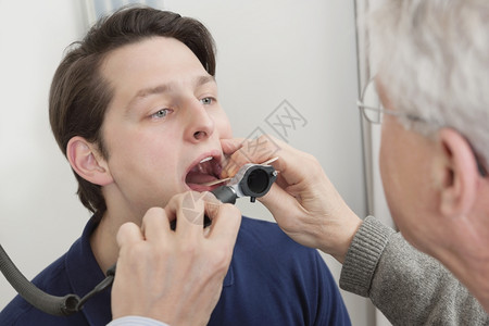 青年男子在诊所接受医生检查其喉咙小舌卫生清理图片